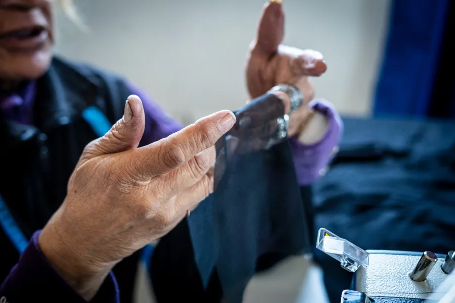 A woman’s hands working fabric beside a sewing machine